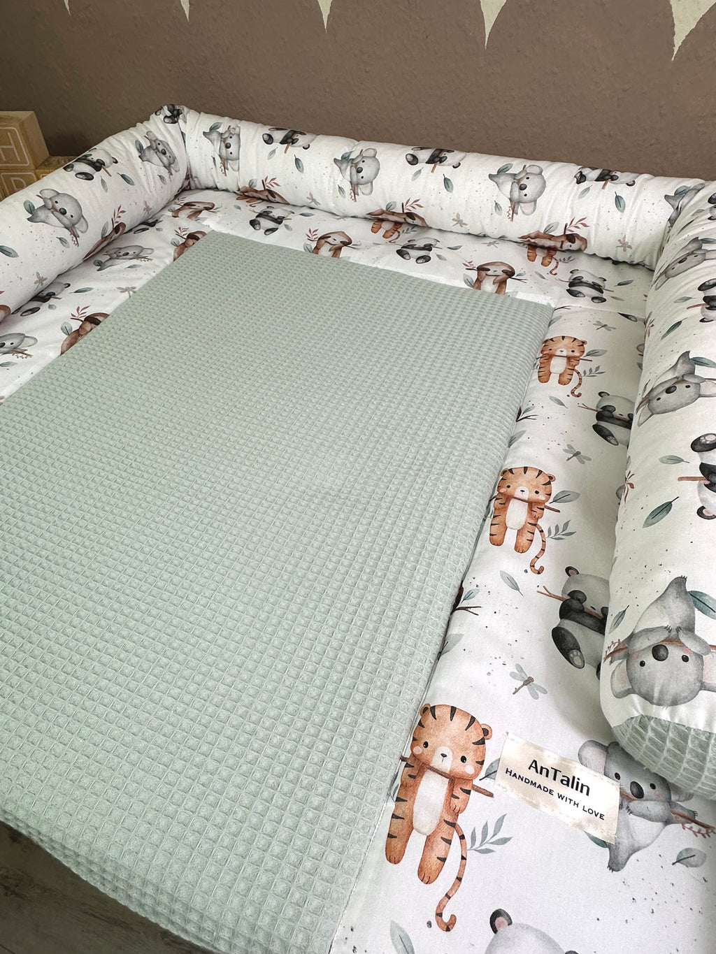 Wickelauflage Animals Friends von AnTalin, waffelpique mit grünen Tiermotiven, weiche und bequeme Unterlage für Babys.