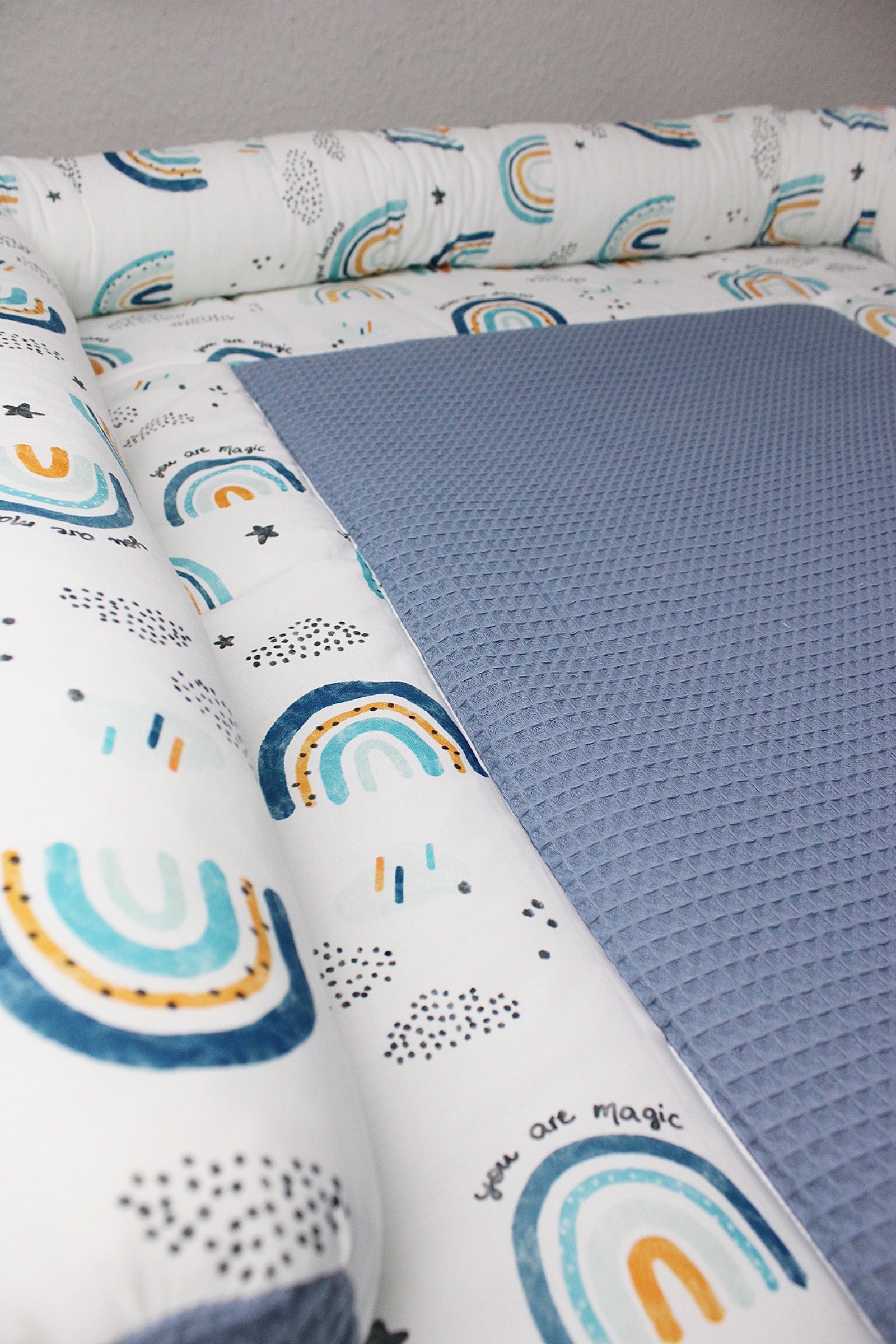 Blaue Wickeltischumrandung mit Regenbogenmotiven von AnTalin, weiches und buntes Stoffdesign für Baby-Wickelbereiche