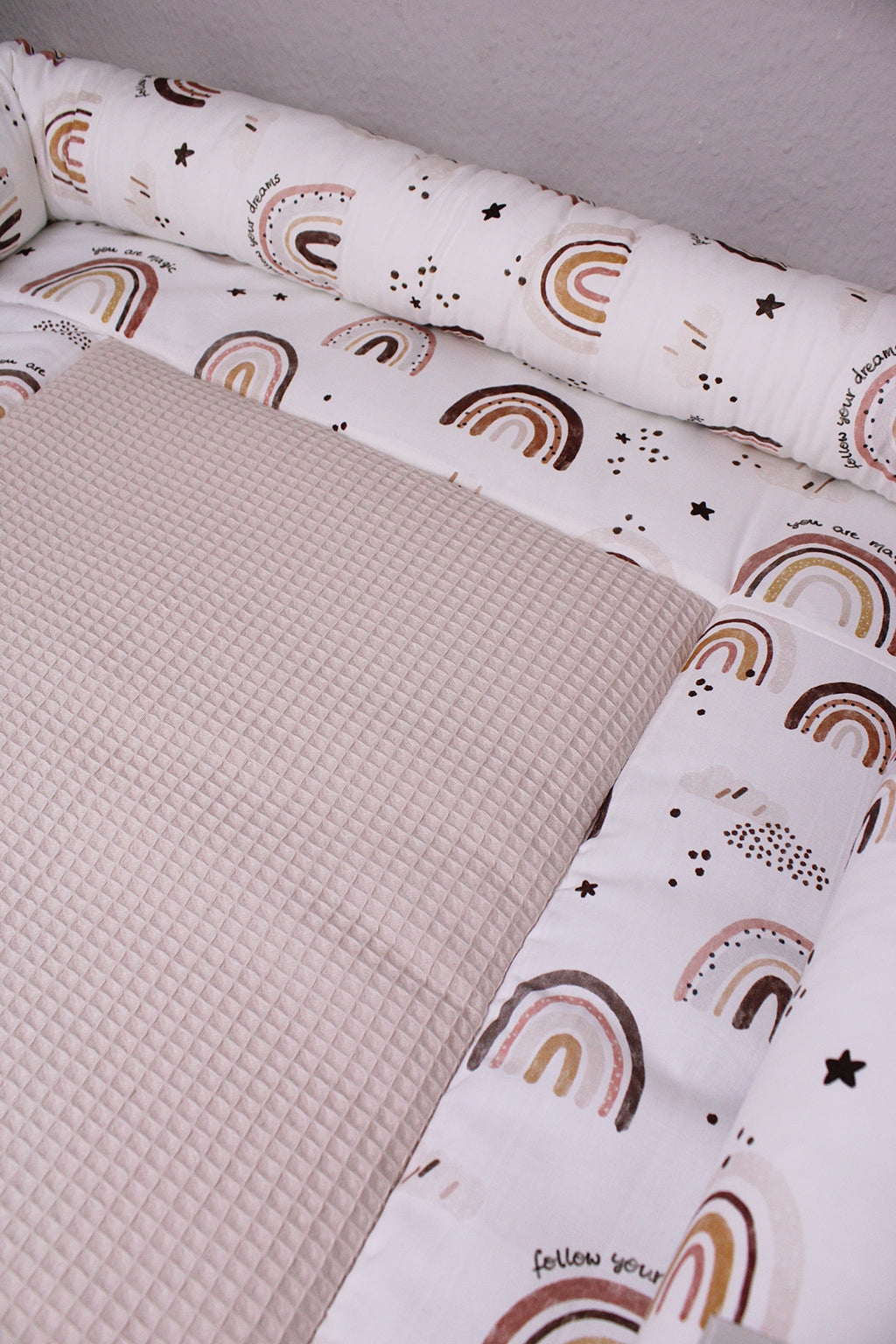 Braune Wickelauflage mit Regenbogenmuster von AnTalin, weich und komfortabel für Babys, auf Wickeltisch gelegt.